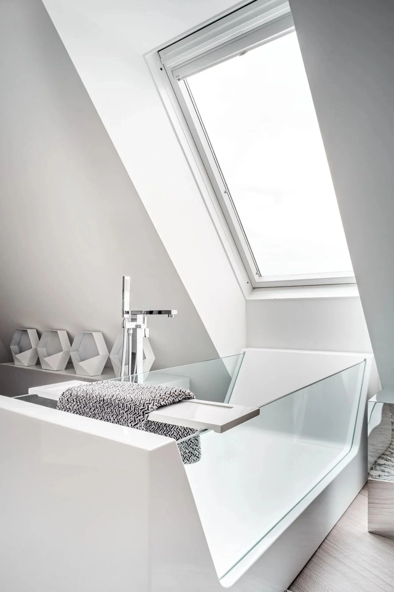 Modernes Dachgeschossbad mit freistehender Badewanne, großem Dachfenster und klarer, minimalistischer Gestaltung in Weiß und Grau – hochwertige Badarchitektur mit ruhiger, heller und stilvoller Spa-Atmosphäre
