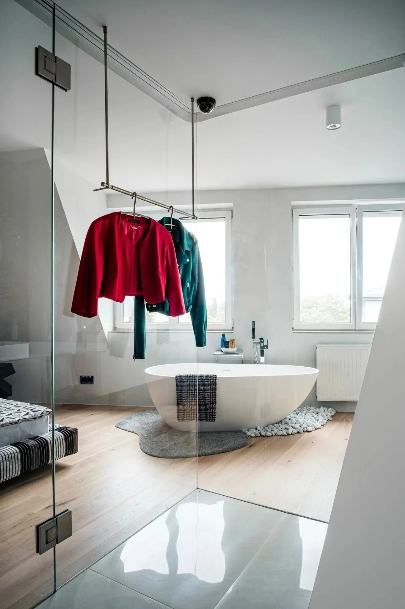 Helles Badezimmer mit freistehender Badewanne und aufgehängten Kleidungsstücken.