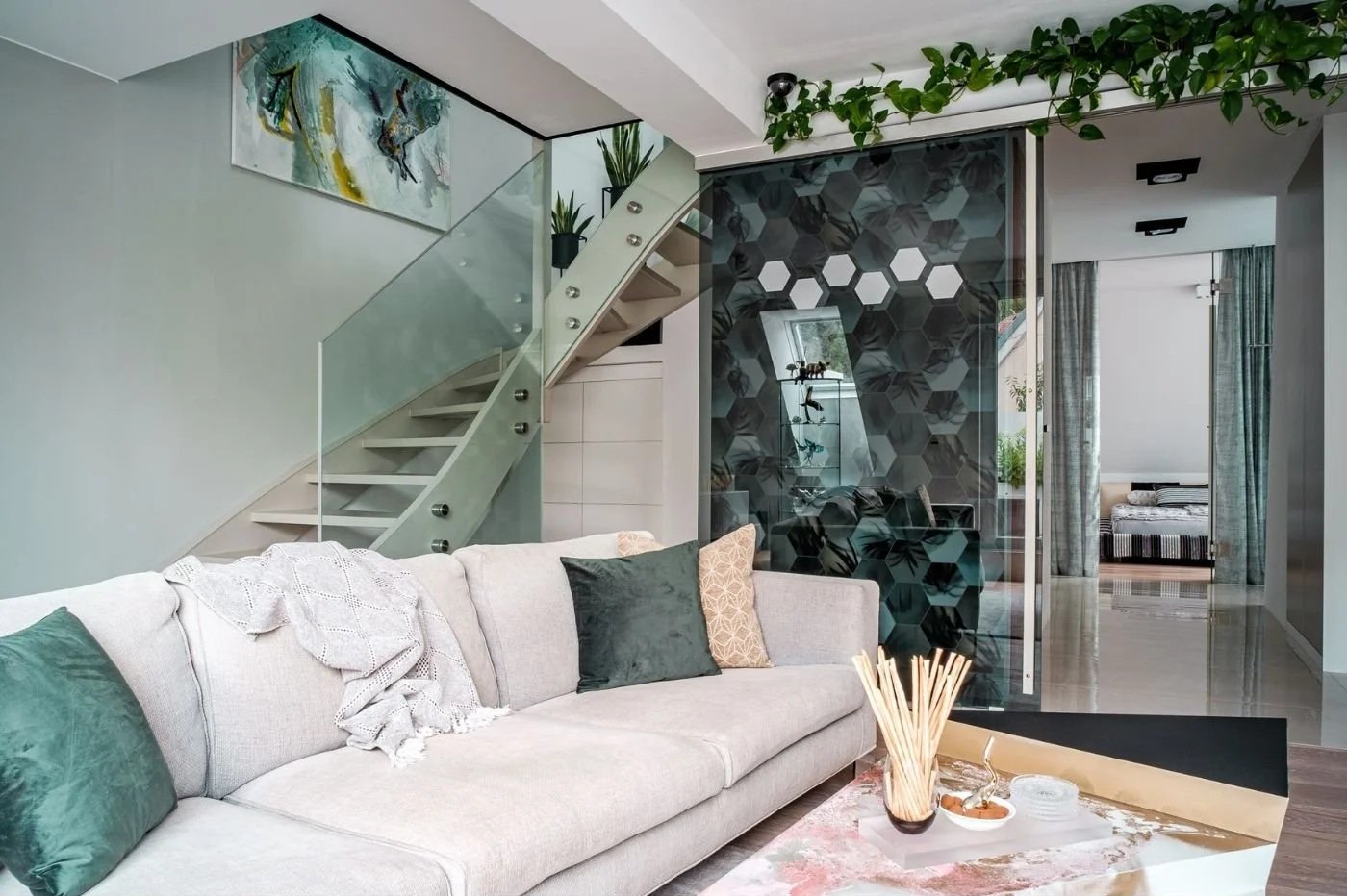 Modernes Wohnzimmer mit heller Couch, Glasstiege, markanter Designerwand und offenem Grundriss – hochwertige Innenarchitektur mit stilvoller Raumwirkung, klarer Linienführung und elegantem Wohnkonzept