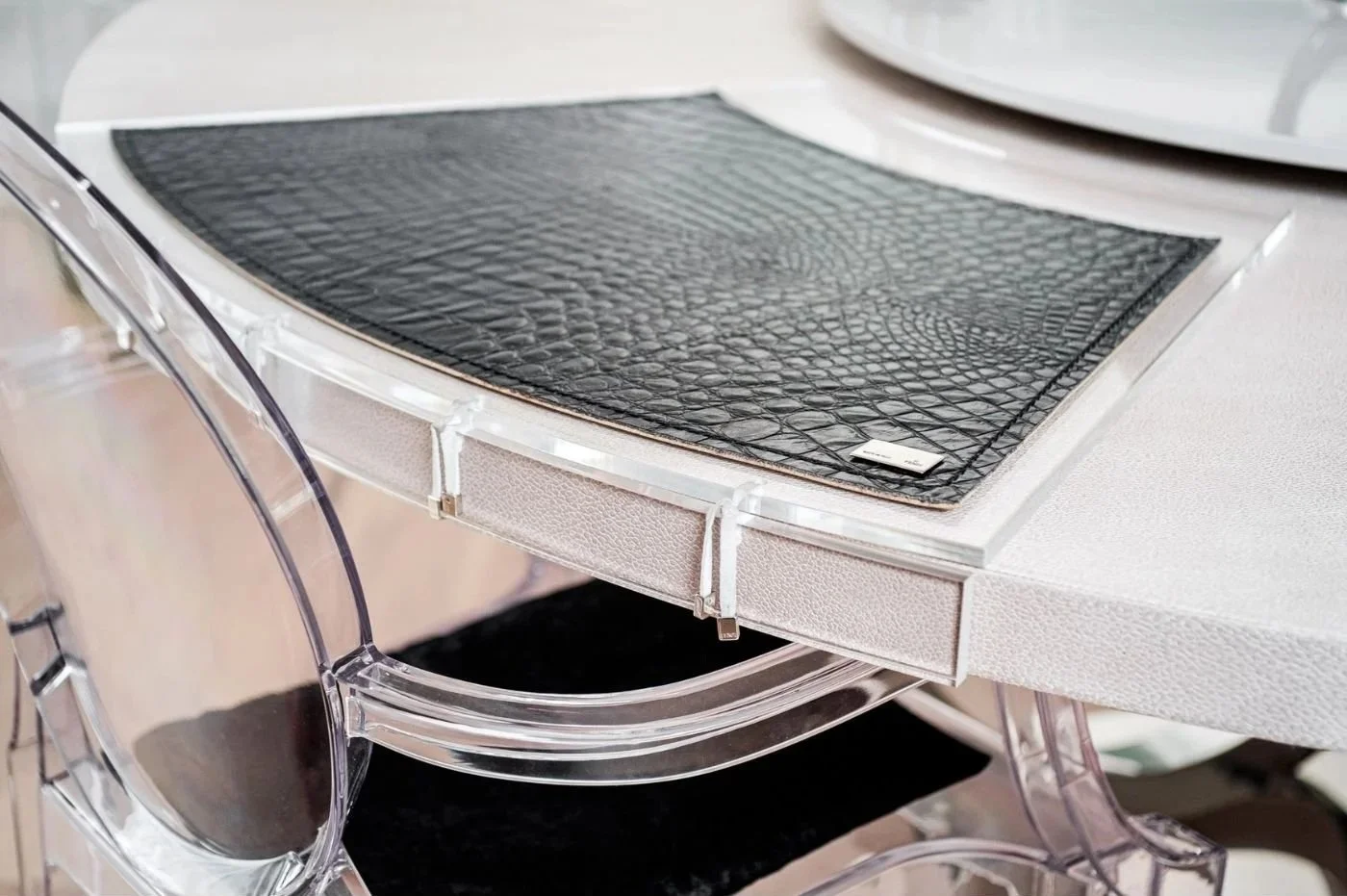 Detail eines Stuhls mit dunkel strukturierter Sitzfläche und glänzendem Metallgestell.
