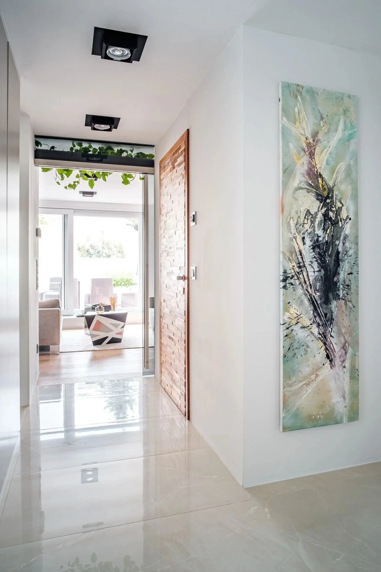Moderner Flur mit großformatigem Kunstbild, glänzendem Boden und offenem Blick in den Wohnbereich – helle Innenarchitektur mit klarer Linienführung, hochwertiger Raumwirkung und stilvoller, einladender Atmosphäre