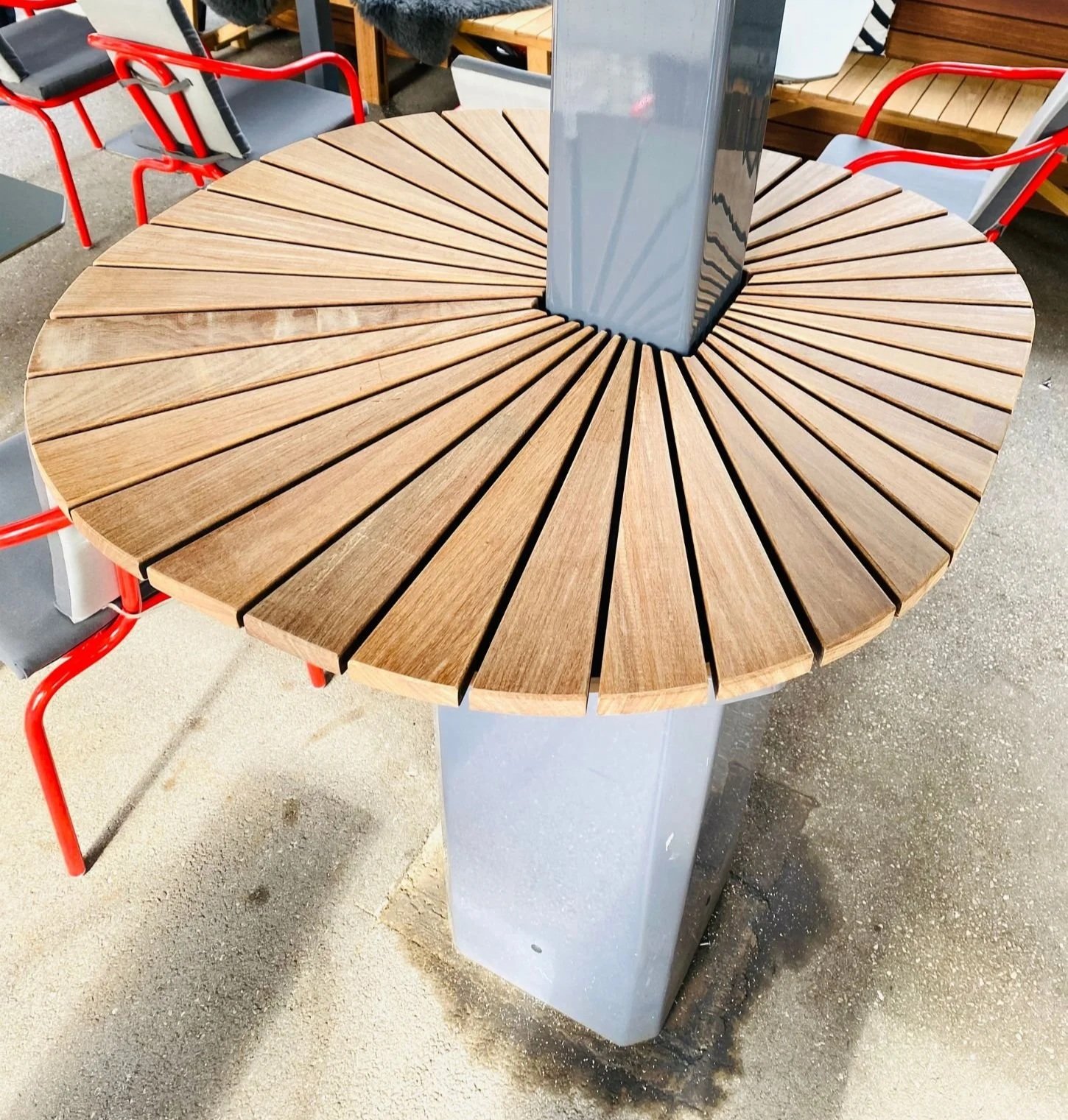 Detailaufnahme einer maßgefertigten runden Holzablage rund um den Sonnenschirm im Gastgarten – funktionales und stilvolles Terrassendetail mit hochwertiger Holzoptik, durchdachter Flächennutzung und individueller Gestaltung im Gastronomie-Außenbereic
