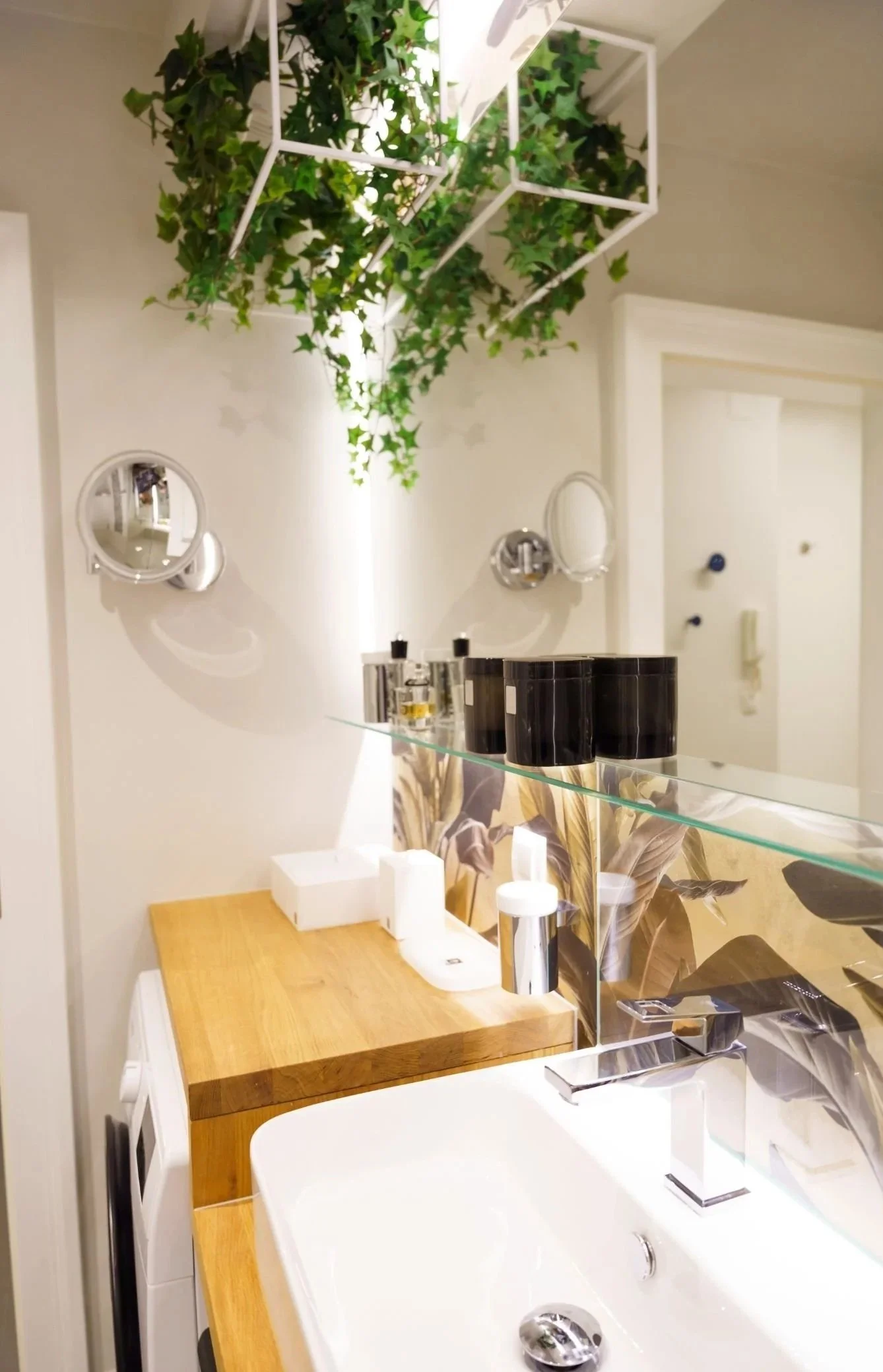 Badezimmer mit Badewanne, Holzablage und hängenden Grünpflanzen