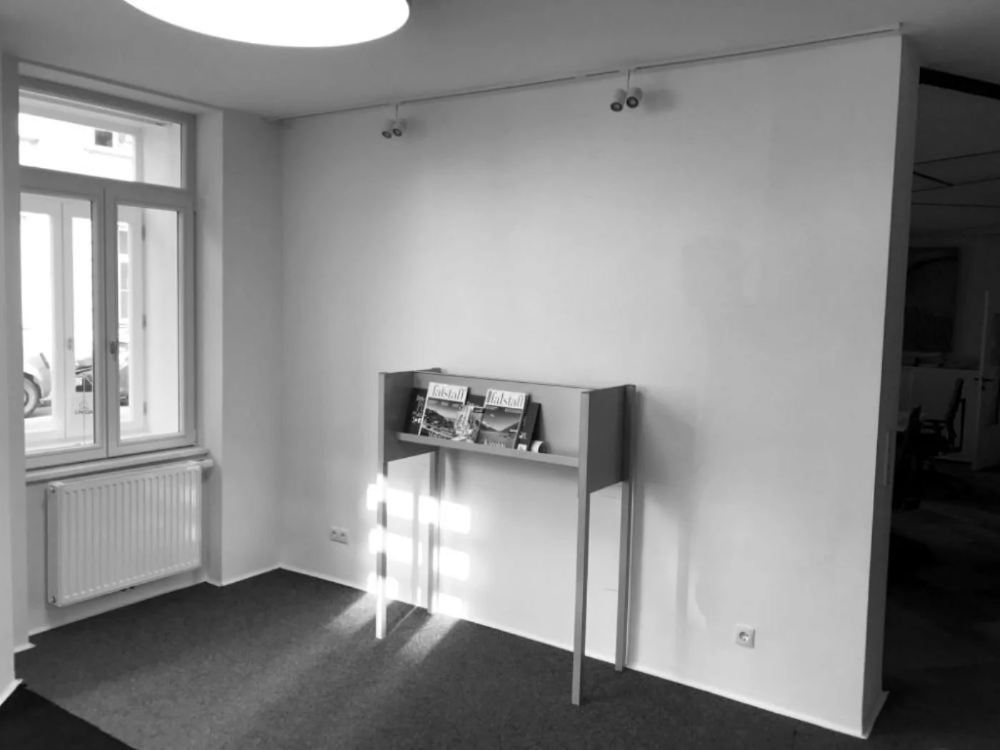 Vorher-Bild eines Kundeneingangsbereichs im Bestandszustand mit schlichter Möblierung, leerer Wandfläche und wenig einladender Atmosphäre – Ausgangssituation vor der Neugestaltung zu einem offeneren und freundlicheren Empfangsbereich