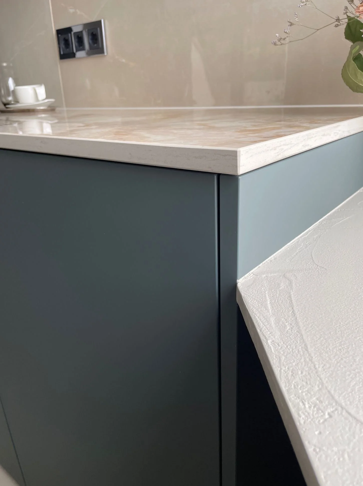 Detailansicht der Kücheninsel: helle Dekton-Arbeitsplatte mit sauberer Abschlusskante über mattschwarzen, grifflosen Fronten - Küchenplanung und Materialberatung in Wien und Umgebung