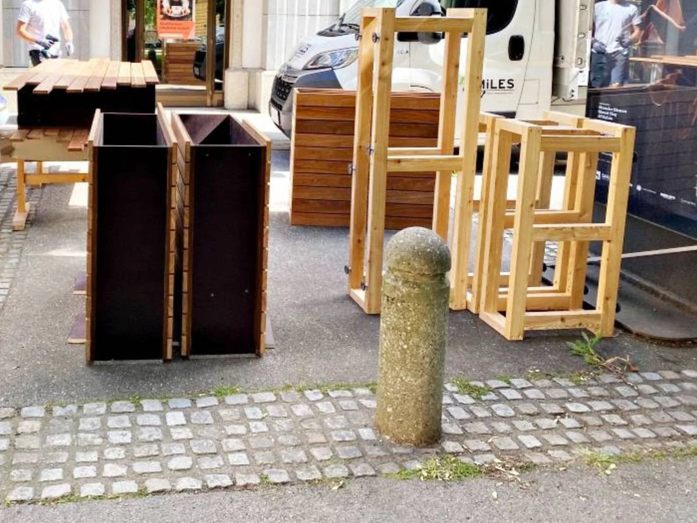 Aufbauphase eines modernen Gastgartens mit Holzgestellen, Pflanzenkästen und maßgefertigten Elementen vor einer Restaurantfassade in Maribor - hochwertige Sonderanfertigung für einen stilvoll gestalteten Außenbereich mit klarer, funktionaler Linienfü