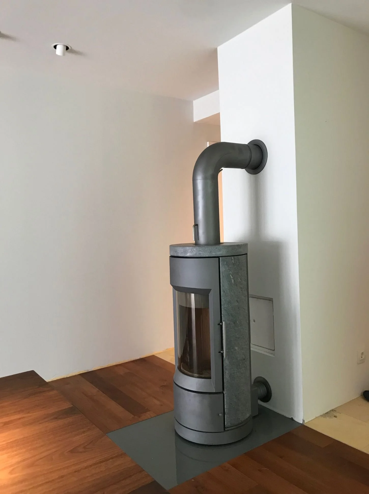 Vorher-Bild eines Kaminofens im Wohnzimmer mit Vollholzparkett als Ausgangssituation vor der Umgestaltung