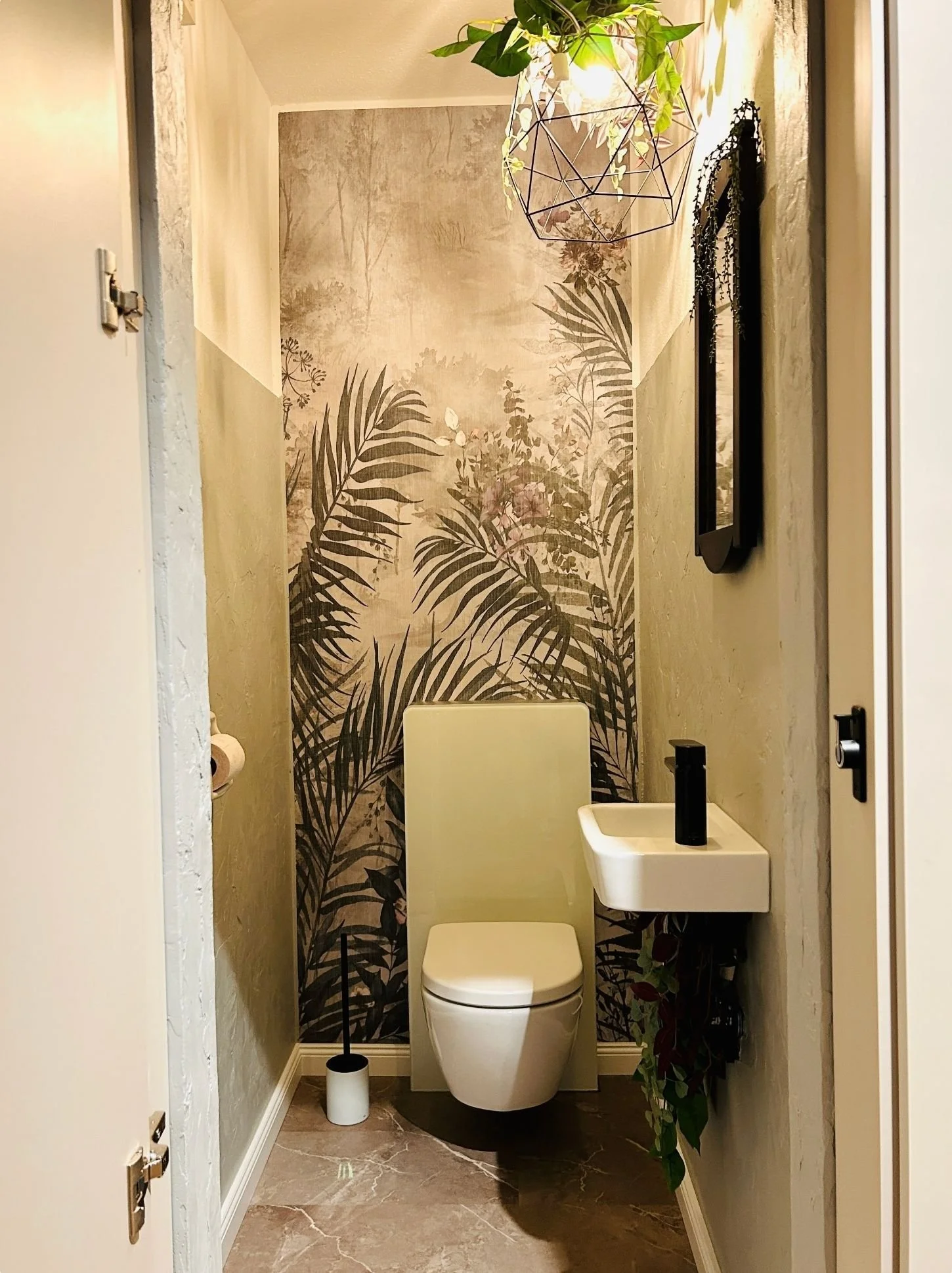 Nachher-Bild eines modernisierten kleinen WCs mit stilvoller Wandgestaltung, wandhaengendem WC und kompaktem Waschbecken