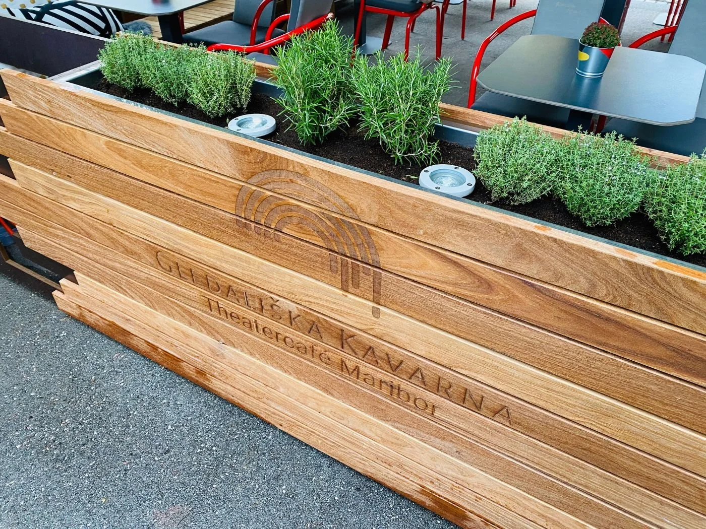 Moderner Gastgarten mit hochwertigem Holzsichtschutz, integriertem Pflanzenkasten und stilvoller Terrassengestaltung vor Restaurant-Sitzplätzen eines Theatercafes in Maribor Gledaliska Kavarna - einladender Außenbereich für Gastronomie und Gäste