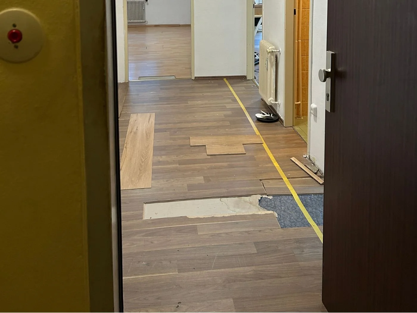 Vorher-Bild eines Flurs in einer Wohnung mit altem dunklem Bodenbelag während der Bodenrenovierung vor dem Verlegen des neuen Vinylbodens
