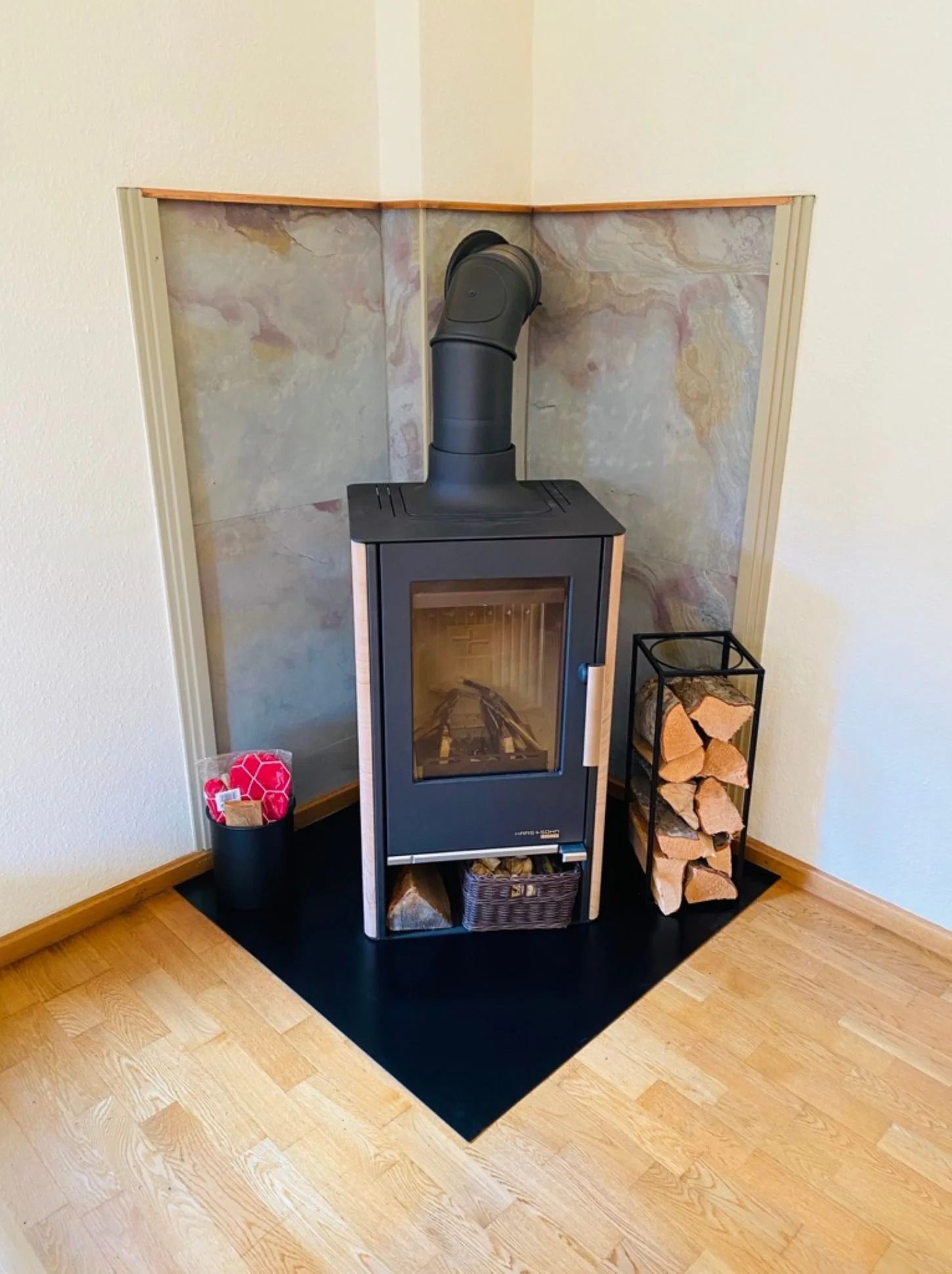 Nachher-Bild eines modernisierten Ofenbereichs mit neuem Kaminofen, neuer Verkleidung und wohnlicher Aufwertung der Raumecke