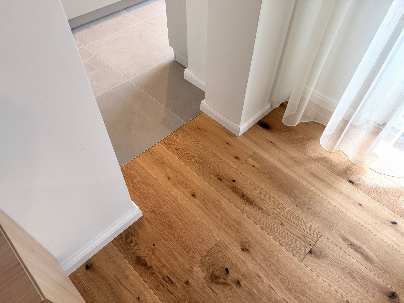 Neu verlegter Boden in Holzoptik im Innenraum mit Einblick in die Verlegearbeiten und das fertige Ergebnis im Wohnbereich
