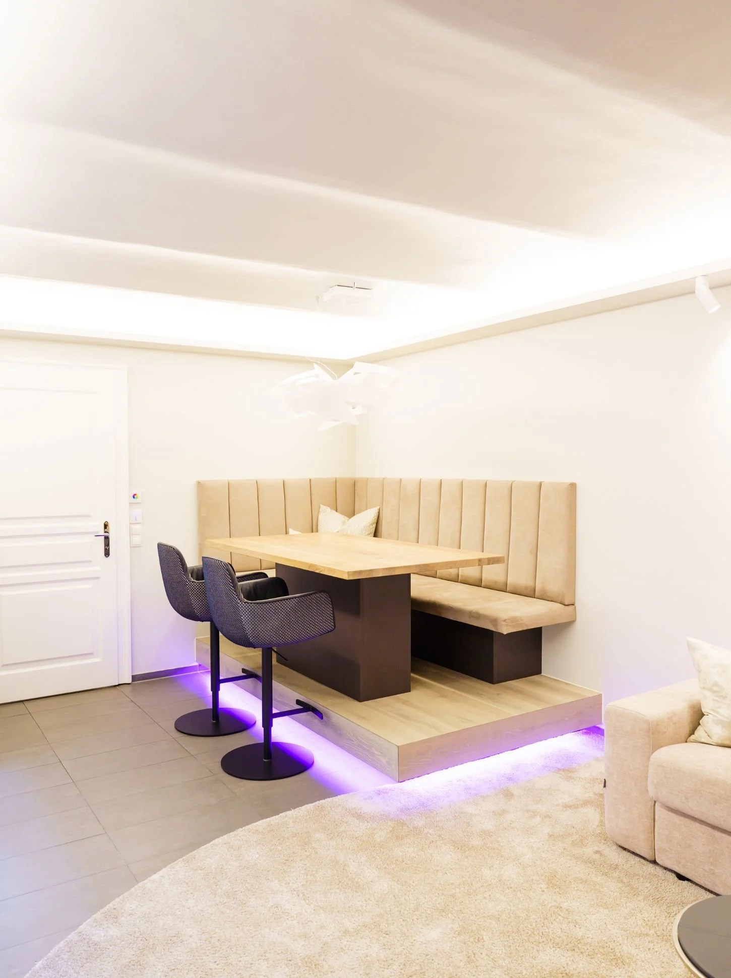 Moderner, offener Essbereich im Wohnzimmer mit maßangefertigter Sitzbank mit Nubuk-Bezug, Barstühlen und indirekter, dimmbarer RGB-Beleuchtung für einen hochwertigen, edlen Luxus-Look - Sanierung und Renovierung
