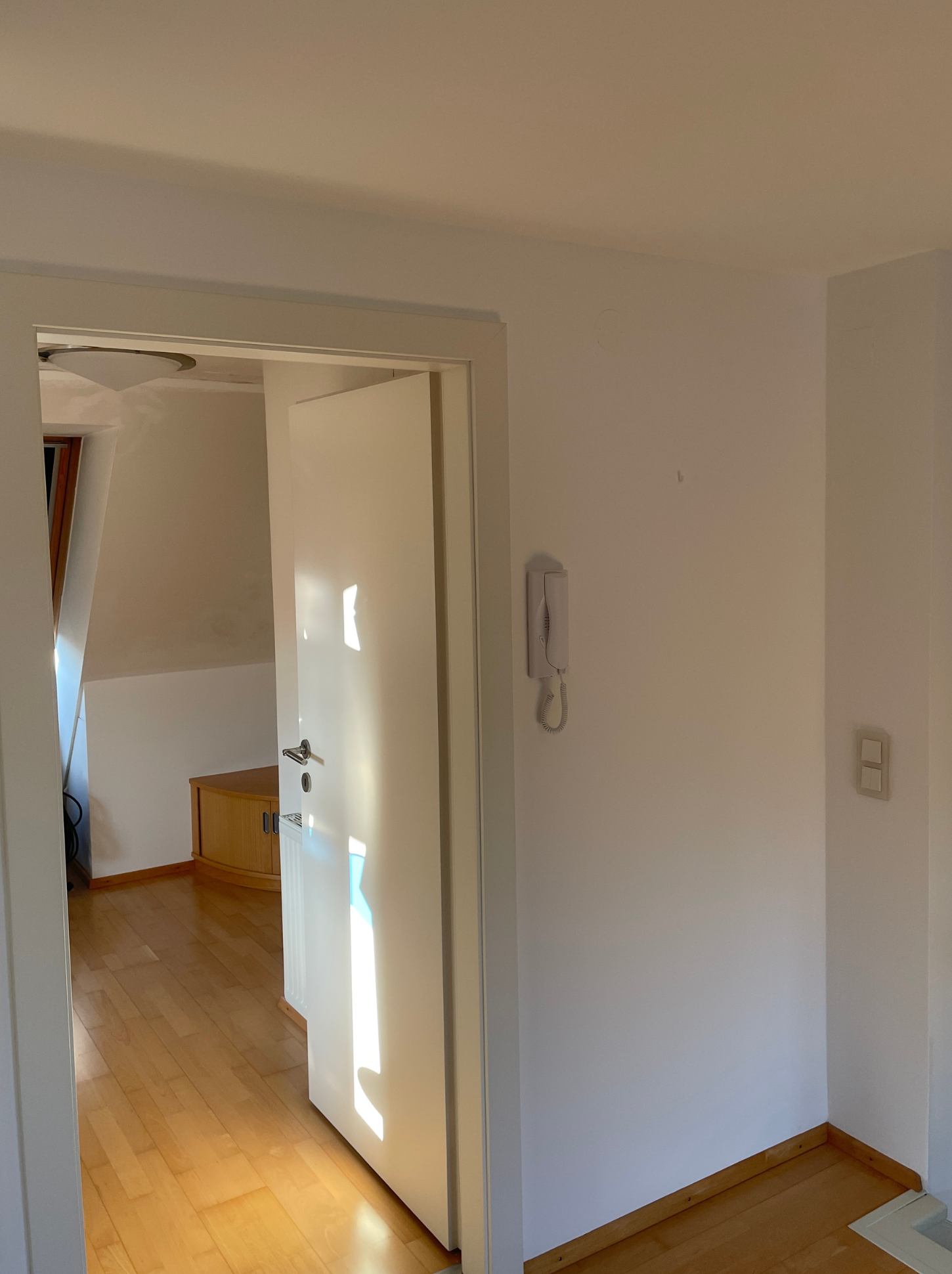 Vorher-Bild eines schlichten Vorzimmers mit weißer Wand, Türnische und wenig gestalterischer Wirkung vor der farblichen Neugestaltung