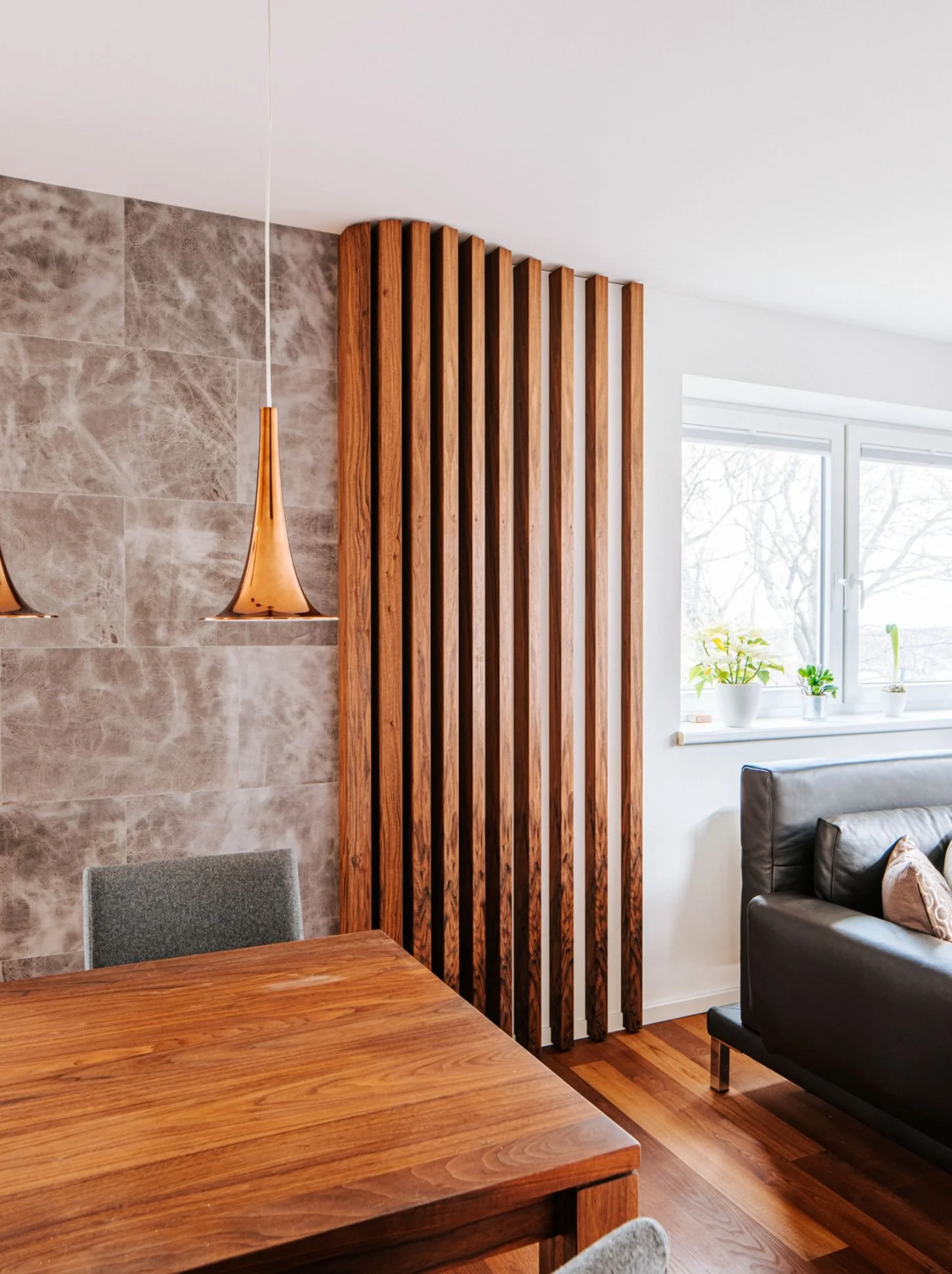Holzlamellen als stilvoller Raumteiler im Wohnzimmer mit Vollholztisch, Naturmaterialien, Designwand und moderner Innenarchitektur für warmes, hochwertiges Wohnen