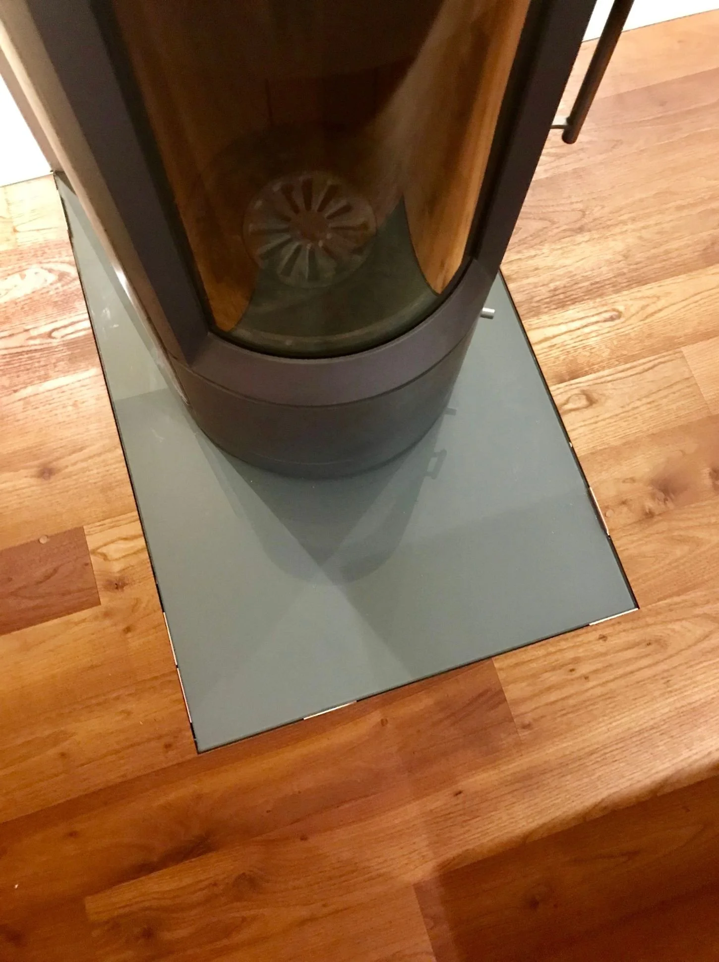Detailaufnahme eines Kaminofens auf Glasbodenplatte mit Vollholzparkett in einem modern gestalteten Wohnzimmer mit natürlichen Materialien