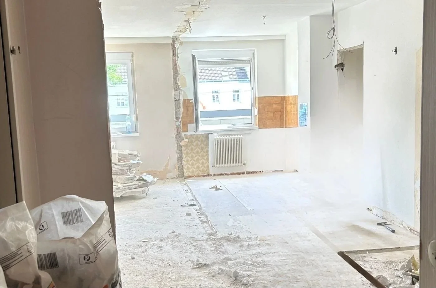 Vorher-Bild eines entkernten Wohnraums während der Renovierung mit freigelegten Wänden und Boden als Ausgangszustand der Innenraumgestaltung