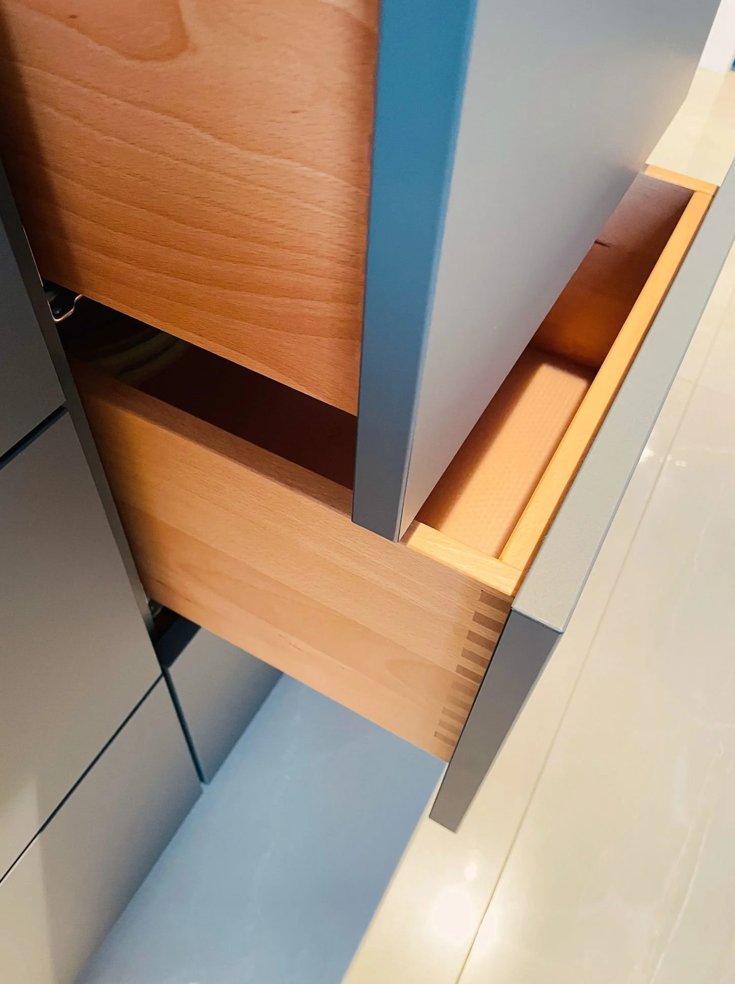 Detailaufnahme einer geöffneten Küchenschublade mit massivem Holzschubkasten als Maßanfertigung einer hochwertigen Designküche - Küchenberatung, Küchenplanung und Küchenmontage in Wien und Umgebung