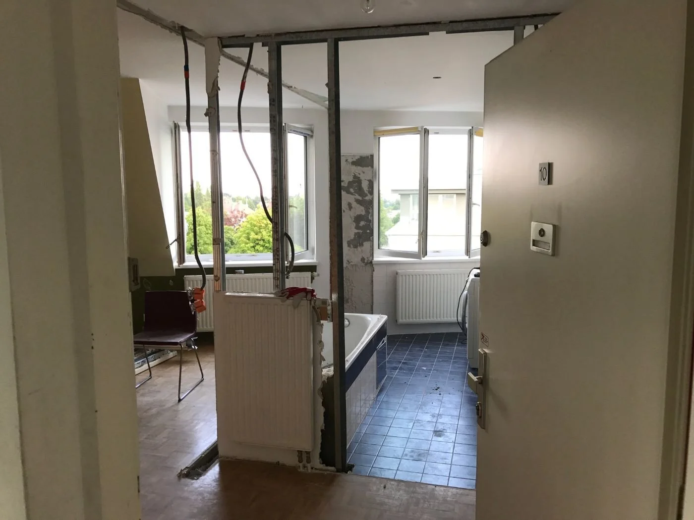 Vorher-Bild eines Badumbaus mit geöffneter Wand, freigelegten Leitungen und teilentkerntem Bestandsbad – bauliche Ausgangssituation vor der Sanierung und Neugestaltung des Badezimmers mit verändertem Grundriss