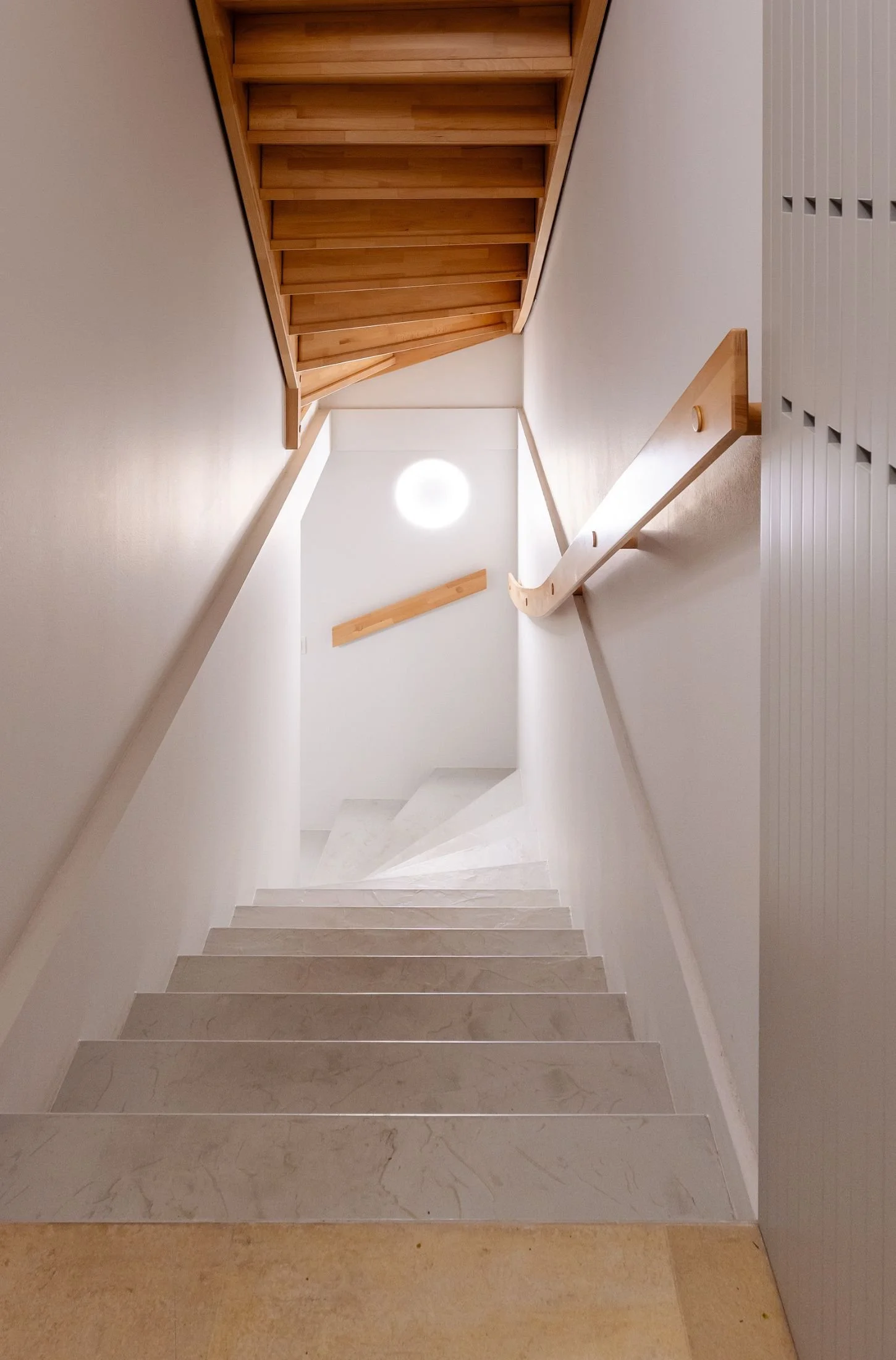 Helles Stiegenhaus mit fugenlos gestalteter Treppe und weißen Wänden