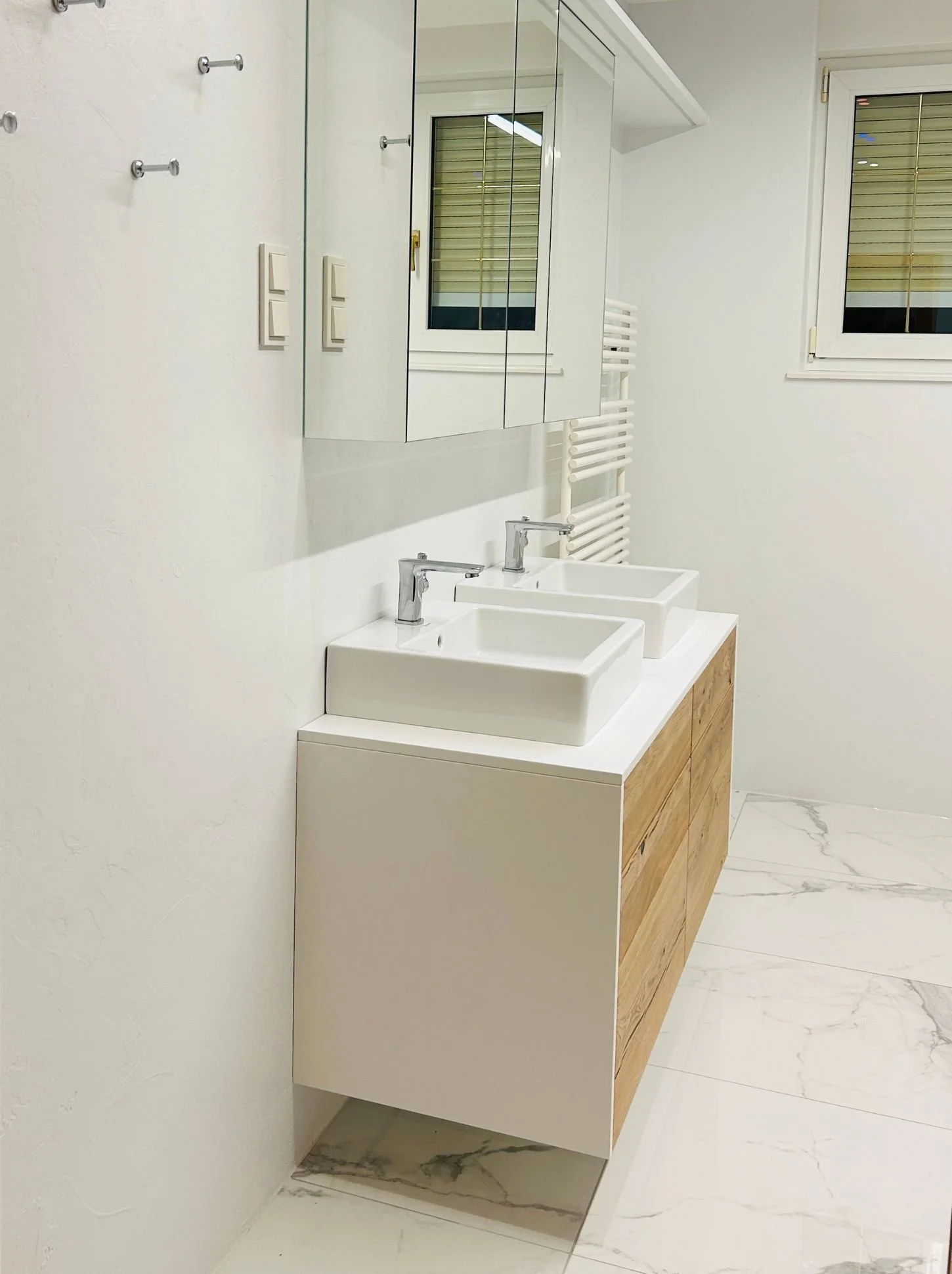 Modernes Badezimmer mit Holzwaschtisch, weißem Aufsatzwaschbecken, Spiegelschrank und fugenlosen Oberflächen