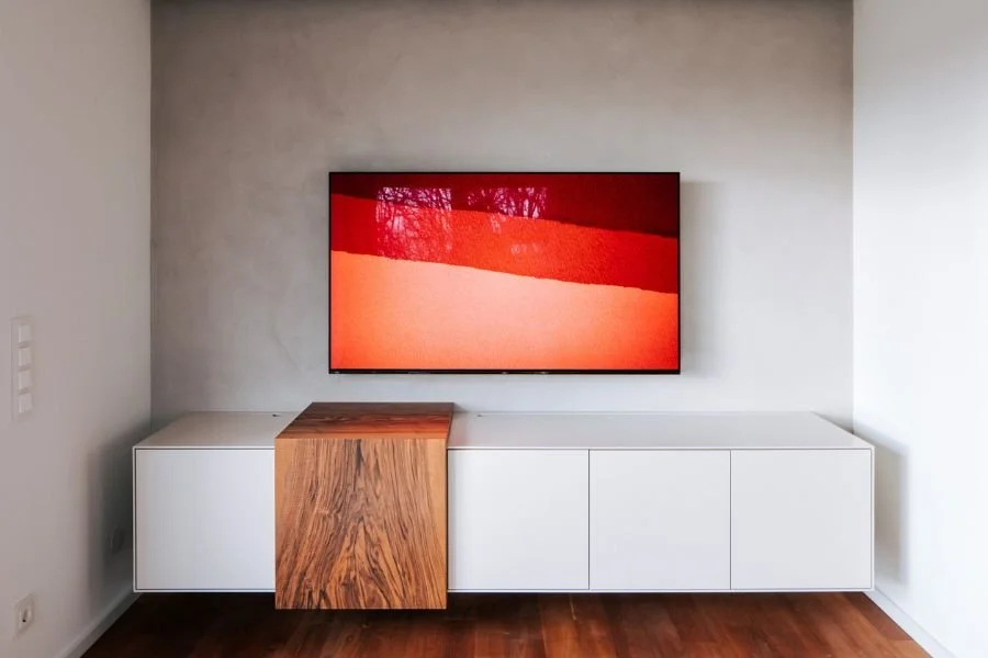 Modernes maßgefertigtes TV-Sideboard in Weiß mit markantem Nußbaum-Element für ein hochwertiges natürliches Wohnzimmerdesign nach Maß