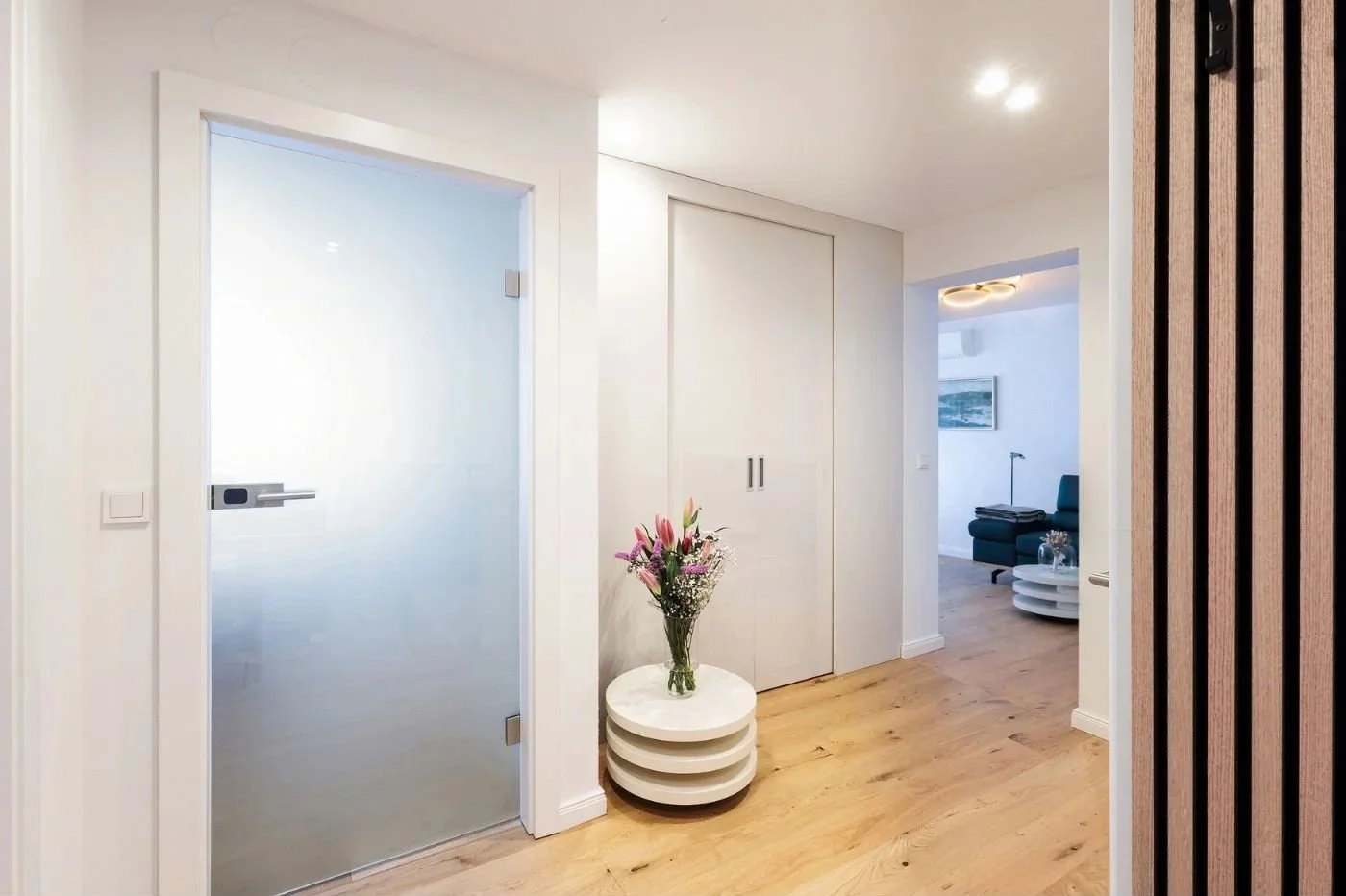 Nachher-Bild eines hellen, modern renovierten Vorraums mit Einbauschrank, Holzfußboden und stilvoller Dekoration – Raumplanung und Interior Design in Wien