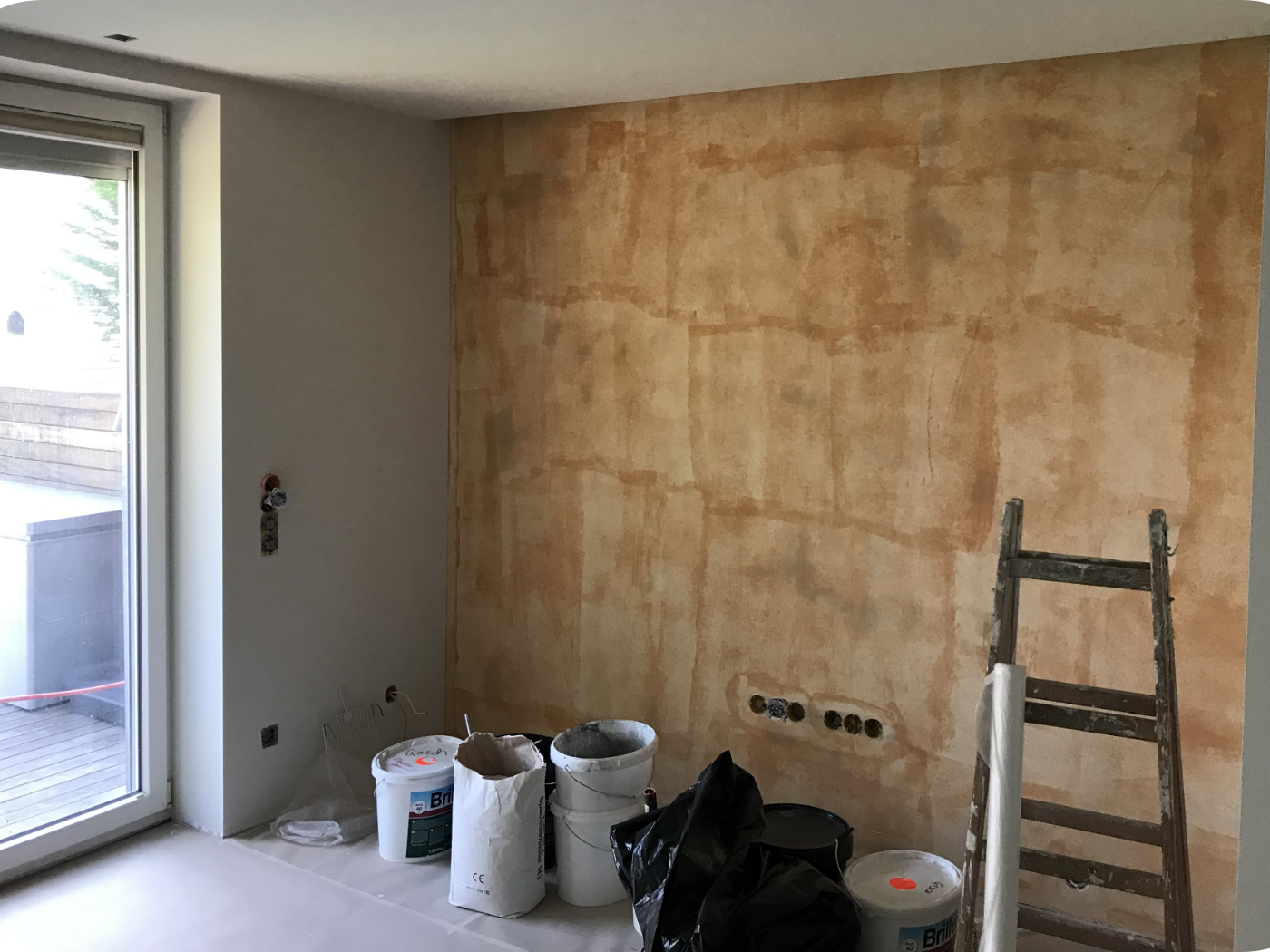 Vorher-Bild einer dunklen und unruhigen Wand als Ausgangssituation vor einer fugenlosen Wandgestaltung