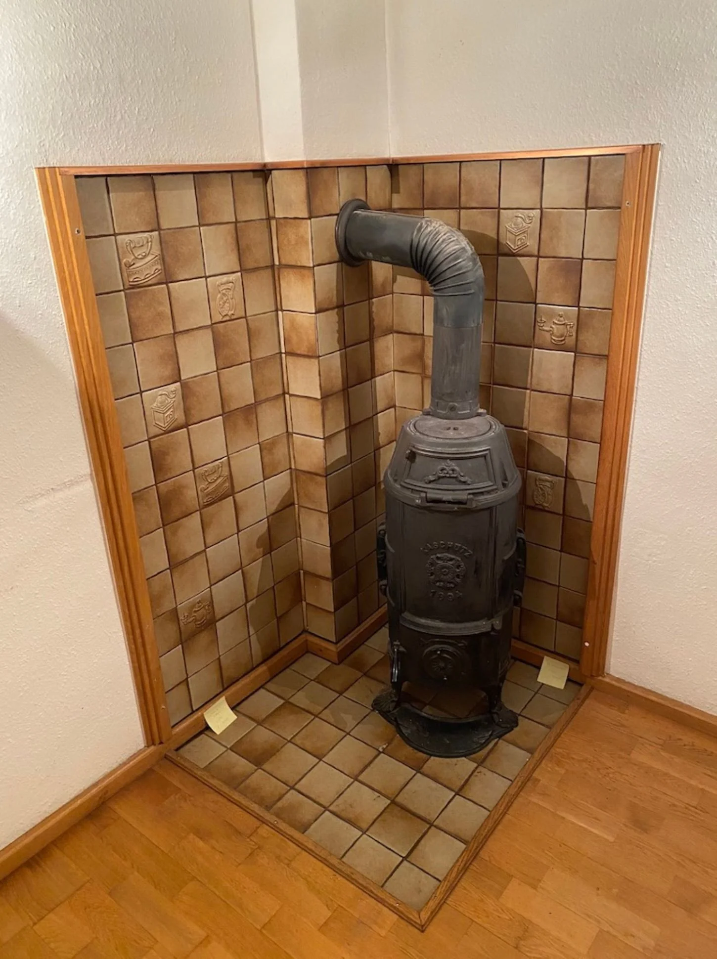 Vorher-Bild einer Kachelofen-Ecke im Bestandsraum vor der Modernisierung des Kaminbereichs und der gestalterischen Raumaufwertung