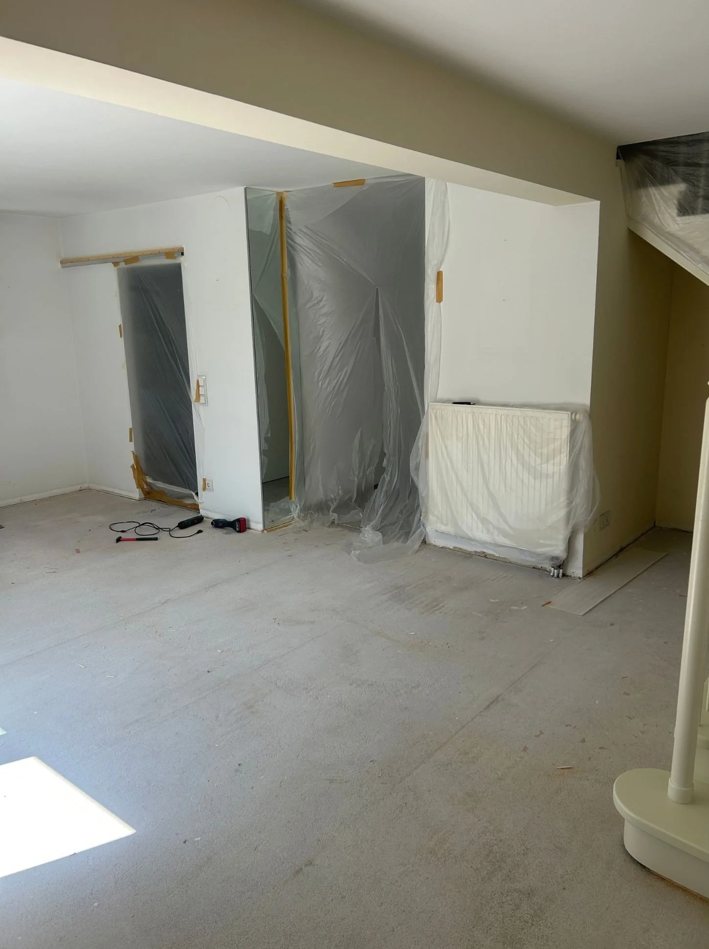 Wohnzimmer während der Sanierung mit entferntem Boden, ausgelagerten Möbeln und Vorbereitung für die Verlegung eines neuen Parketts