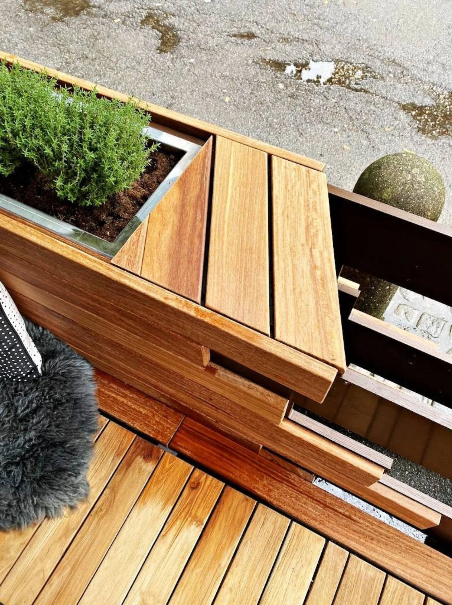 Detailaufnahme eines modernen Gastgartens mit hochwertiger Holzterrasse, Holzbank und integriertem Pflanzenkasten - stilvoll gestalteter Außenbereich einer Gastronomie mit natürlicher Atmosphäre
