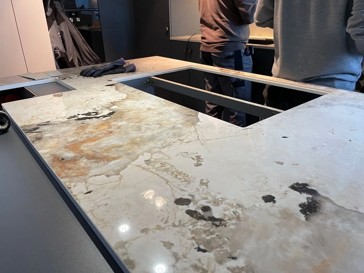 Kücheninsel während der Montage mit auffälliger Marmoroptik und Ausschnitt für ein flächenbündiges Induktionskochfeld - Einbau und Küchenmontage in Wien und Umgebung