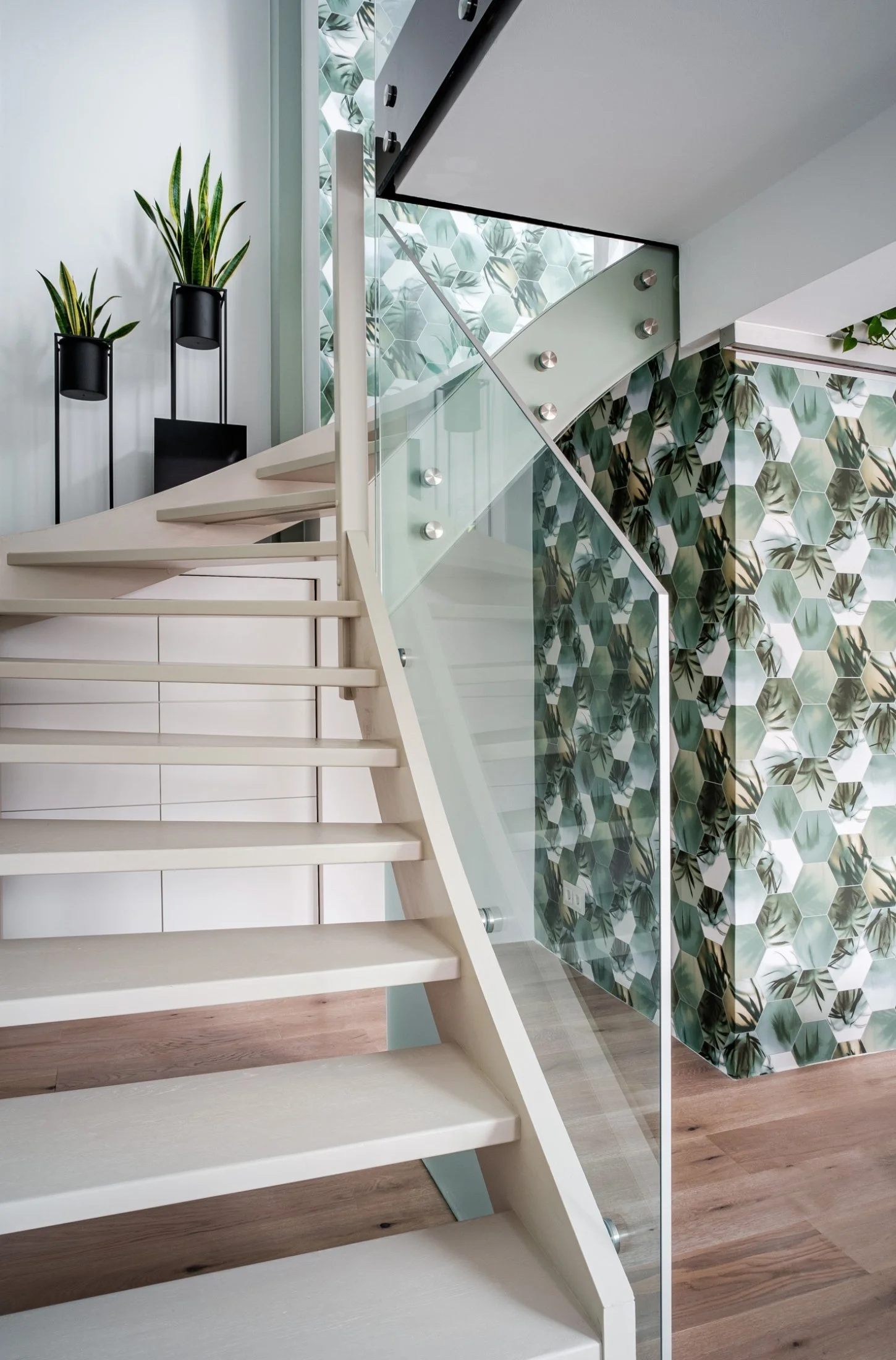 Moderne Treppe mit Glasgeländer und dekorativer Mooswand in einem hellen Innenraum – hochwertige Innenarchitektur mit natürlichem Designakzent und stilvoller, offener Raumwirkung