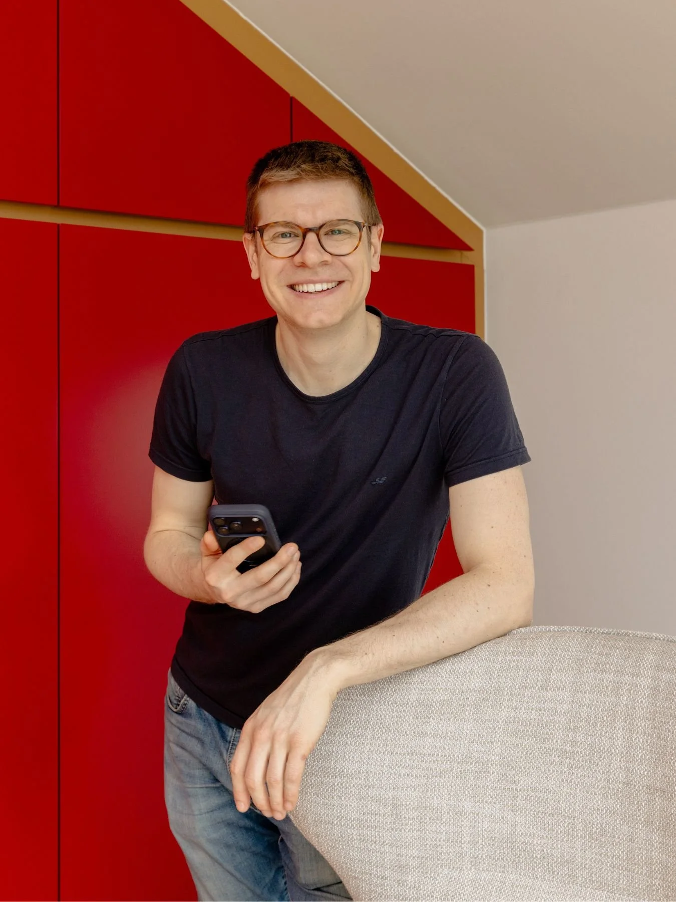 Mann in modern gestaltetem Innenraum mit roten Einbaumöbeln – individuelle Innenarchitektur, Raumplanung und Einrichtungslösungen in Wien