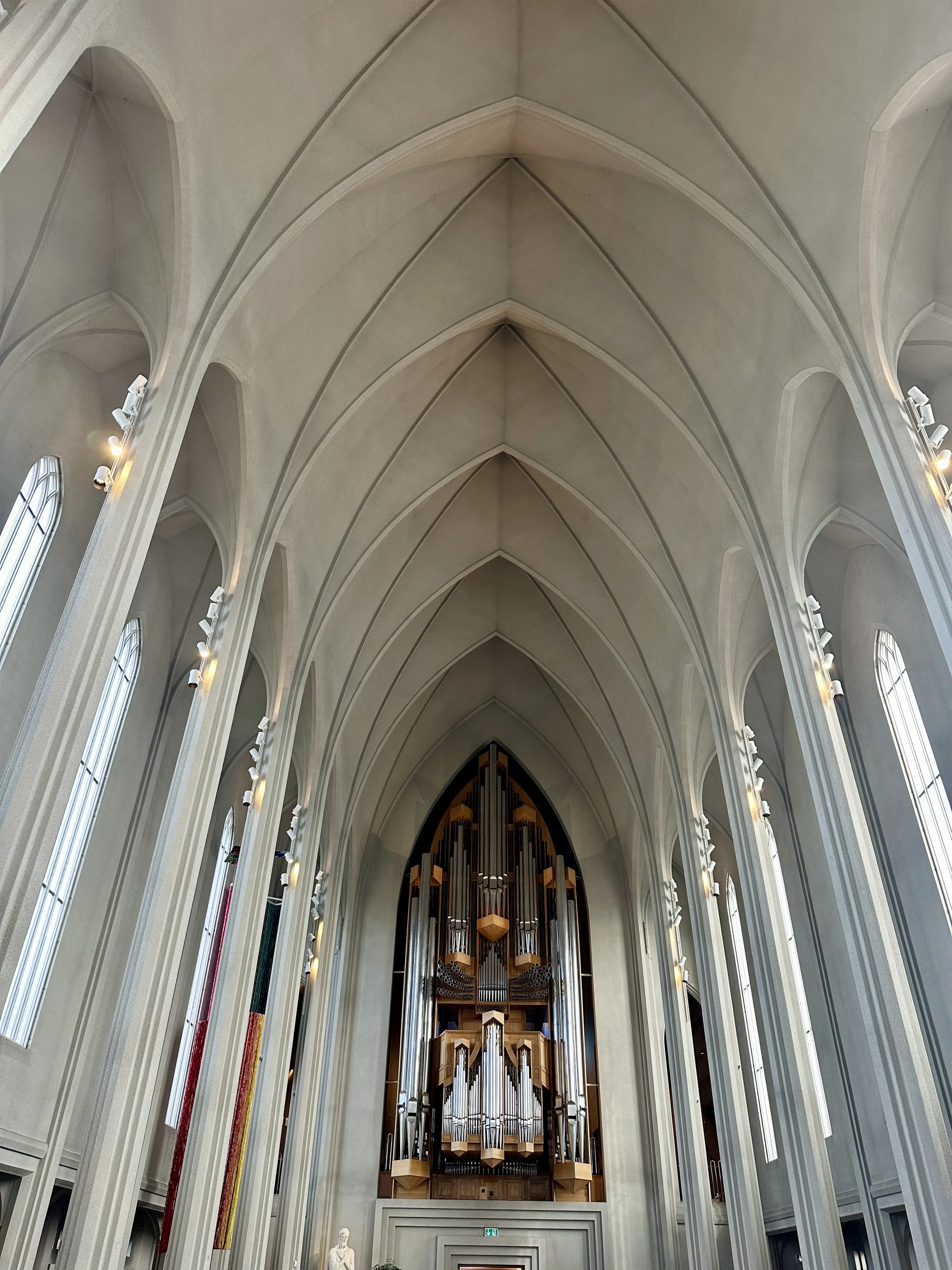 Innenansicht einer Kirche mit hohen geschnitzten Gewölbedecken und einem großen Orgel im Vordergrund.