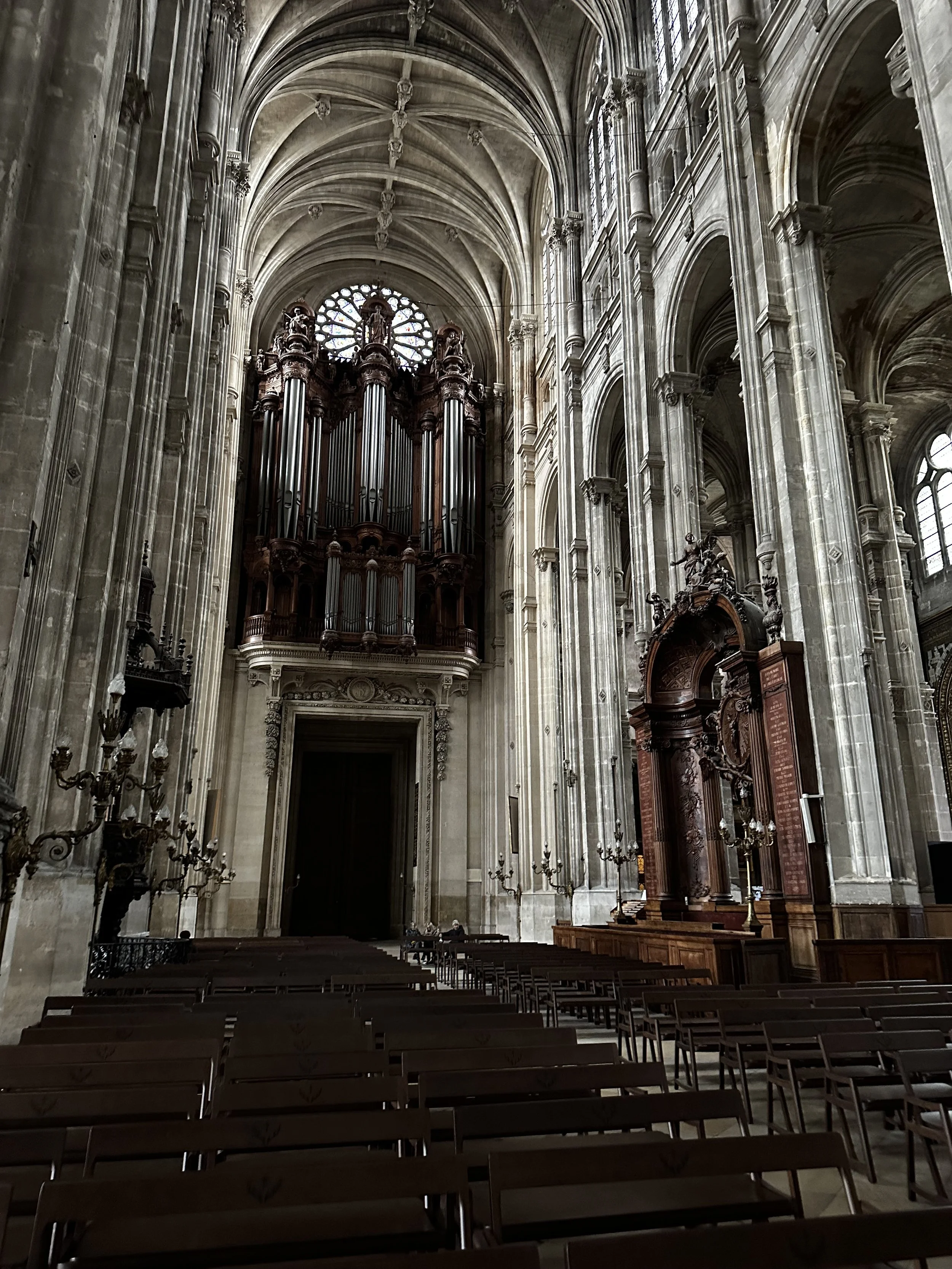 Innenansicht einer gotischen Kathedralkirche mit großen Fenstern, Orgel im Hintergrund und leeren Bänken im Vordergrund.