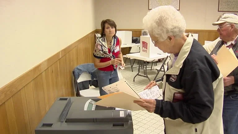 A woman places her paper ballot in a ballot scanner on election day.