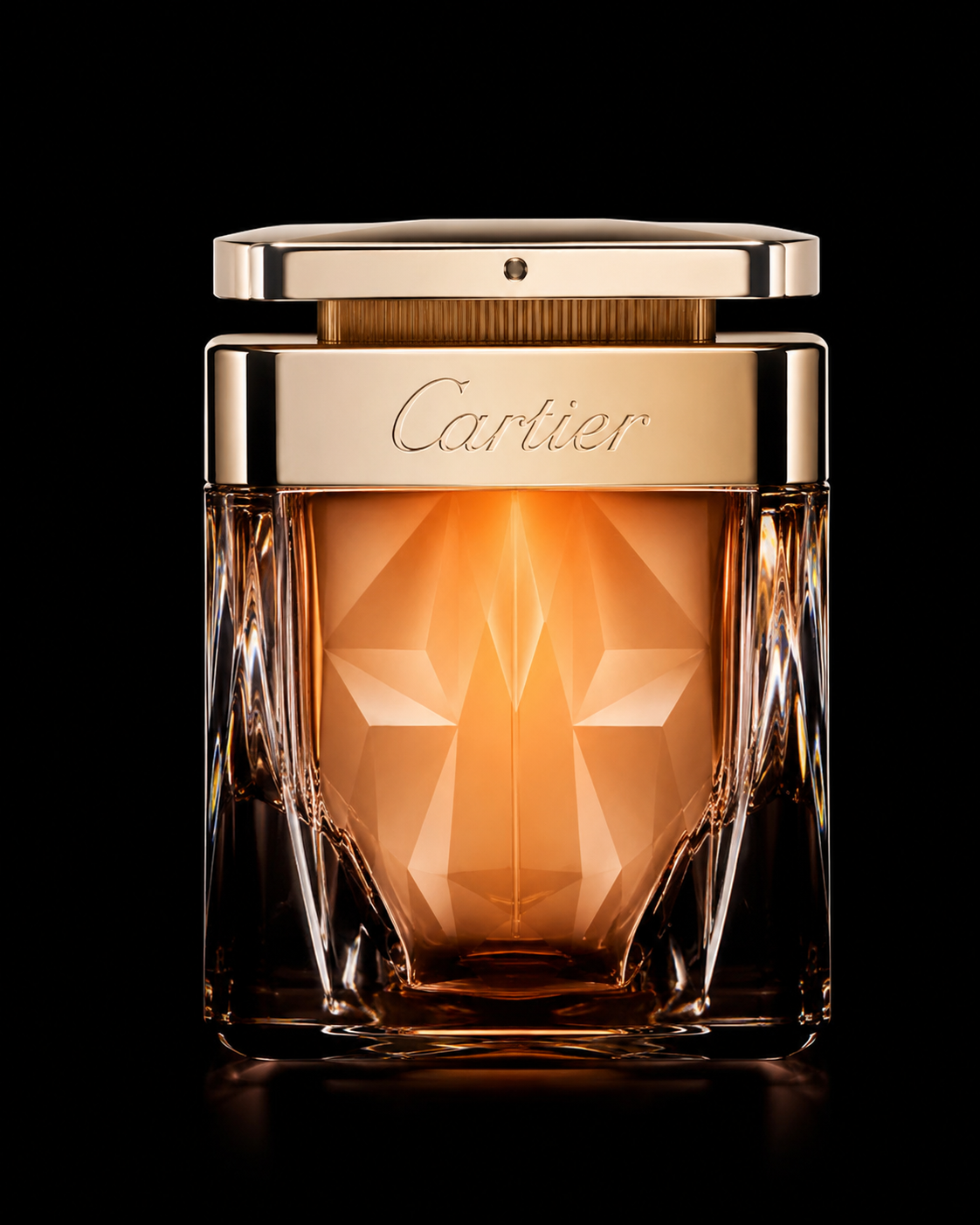 Un flacon de parfum Cartier avec un design en verre facetté, couleur orange, et un capuchon en métal doré sur fond noir.