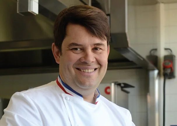 Homme souriant en chef cuisinier dans une cuisine professionnelle.