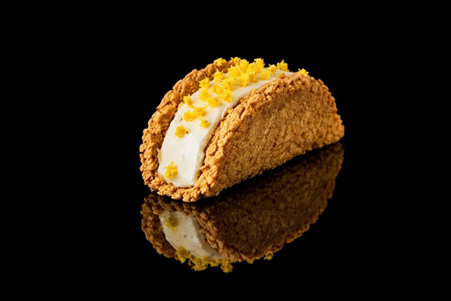 Un taco de crème avec une garniture de zeste de citron ou de citron confit sur un fond noir.