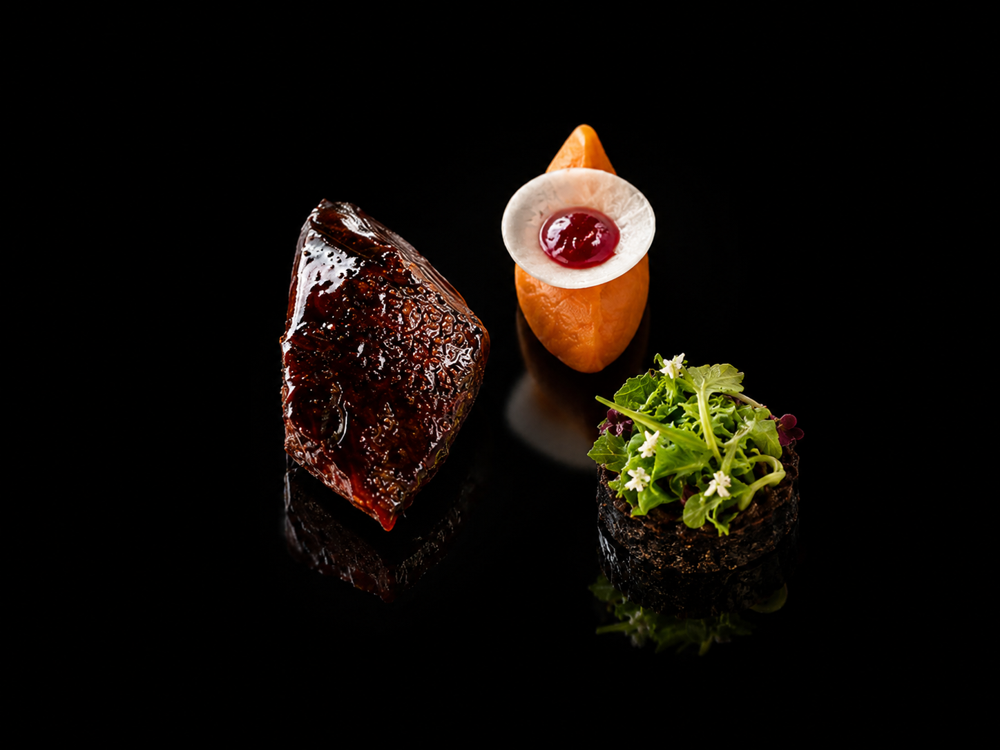 Trois plats de nourriture sophistiquée sur fond noir: un morceau de viande en sauce, un amuse-bouche avec un œuf et une sauce rouge, et un petit pot de salade avec des fleurs et des feuilles vertes.