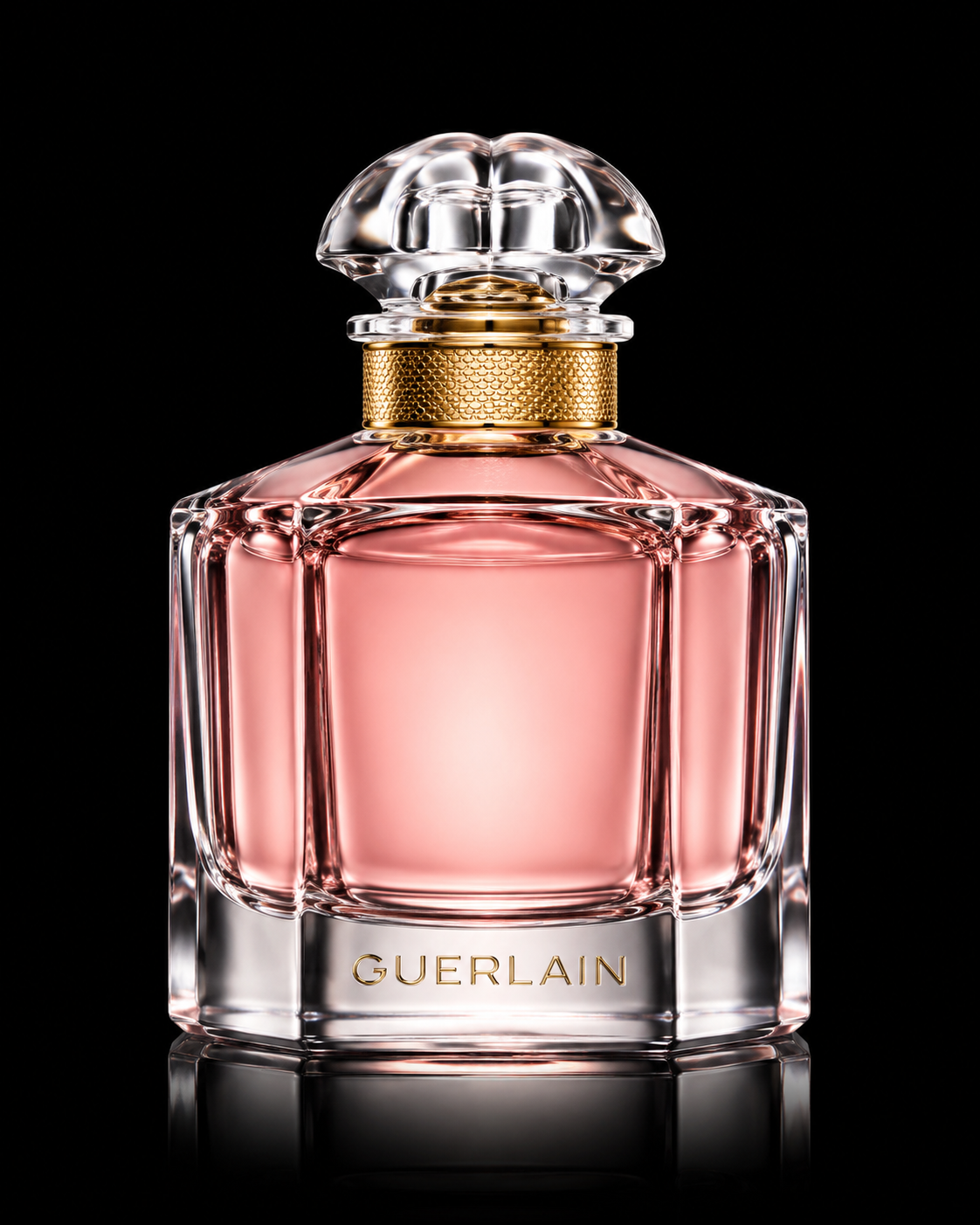 Flacon de parfum Guerlain avec un design élégant en verre, contenant un liquide rose clair, contre un fond noir.