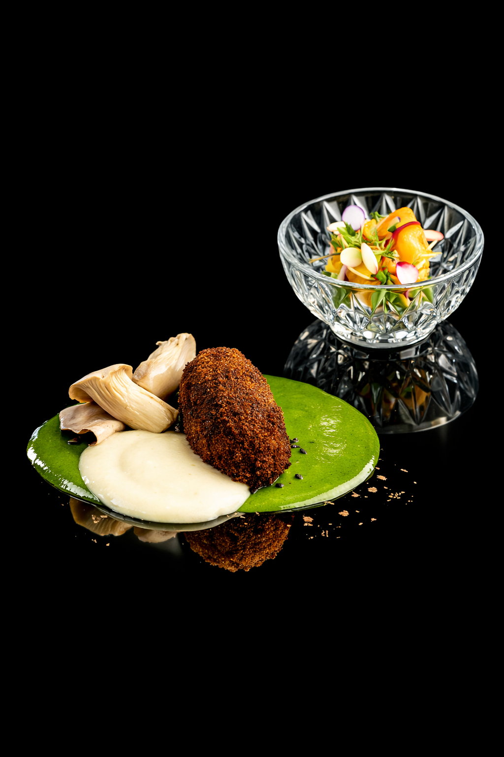 Plat gastronomique avec un croquettes croustillantes, champignons, et sauce blanche sur une feuille de légumes, accompagné d'une salade colorée dans un bol en cristal.