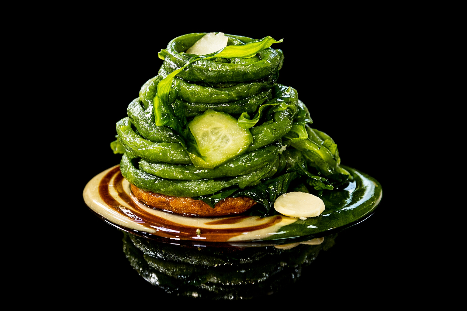 Tortilla avec un empilage de courgettes sautées, garnie de parmesan et d'ail, sur une assiette décorative noire.