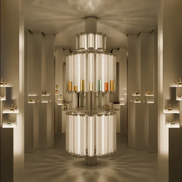 Un chandelier moderne en forme de cylindre, suspendu dans une pièce élégante avec des étagères murales contenant de petits objets.