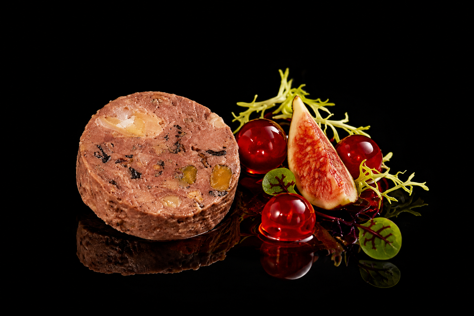 Terrine de viande avec figue, garnie de salade verte, figue fraîche, raisins rouges et gelée sur fond noir.