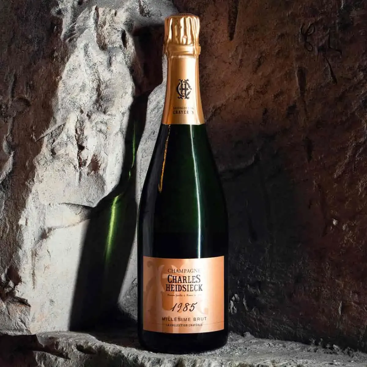 Une bouteille de champagne Charles Heidsieck millésime 1985, posé sur une pierre dans un environnement rocheux.