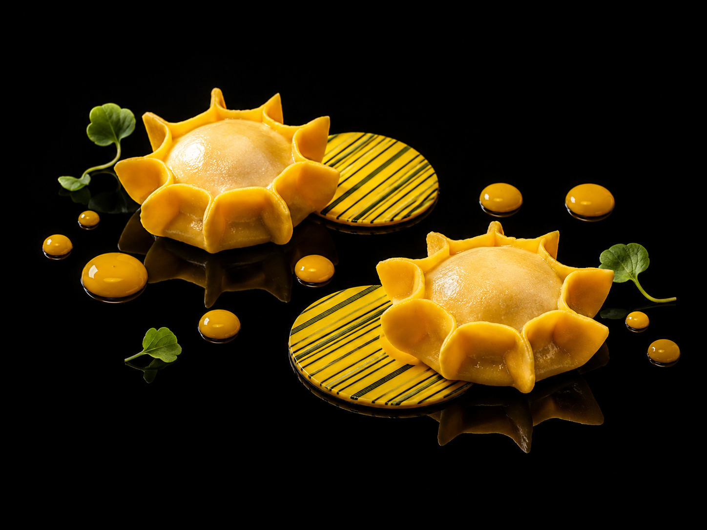 Deux desserts en forme de soleil avec un glaçage lisse, entourés de petites feuilles vertes, accompagnés de cercles de sauce jaune sur un fond noir.