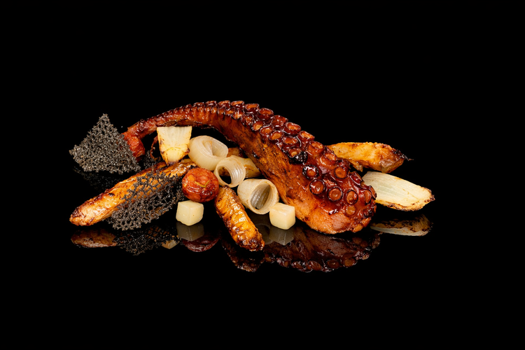 Plat de fruits de mer avec pieuvre grillée, pâtes, légumes et sauces sur un fond noir