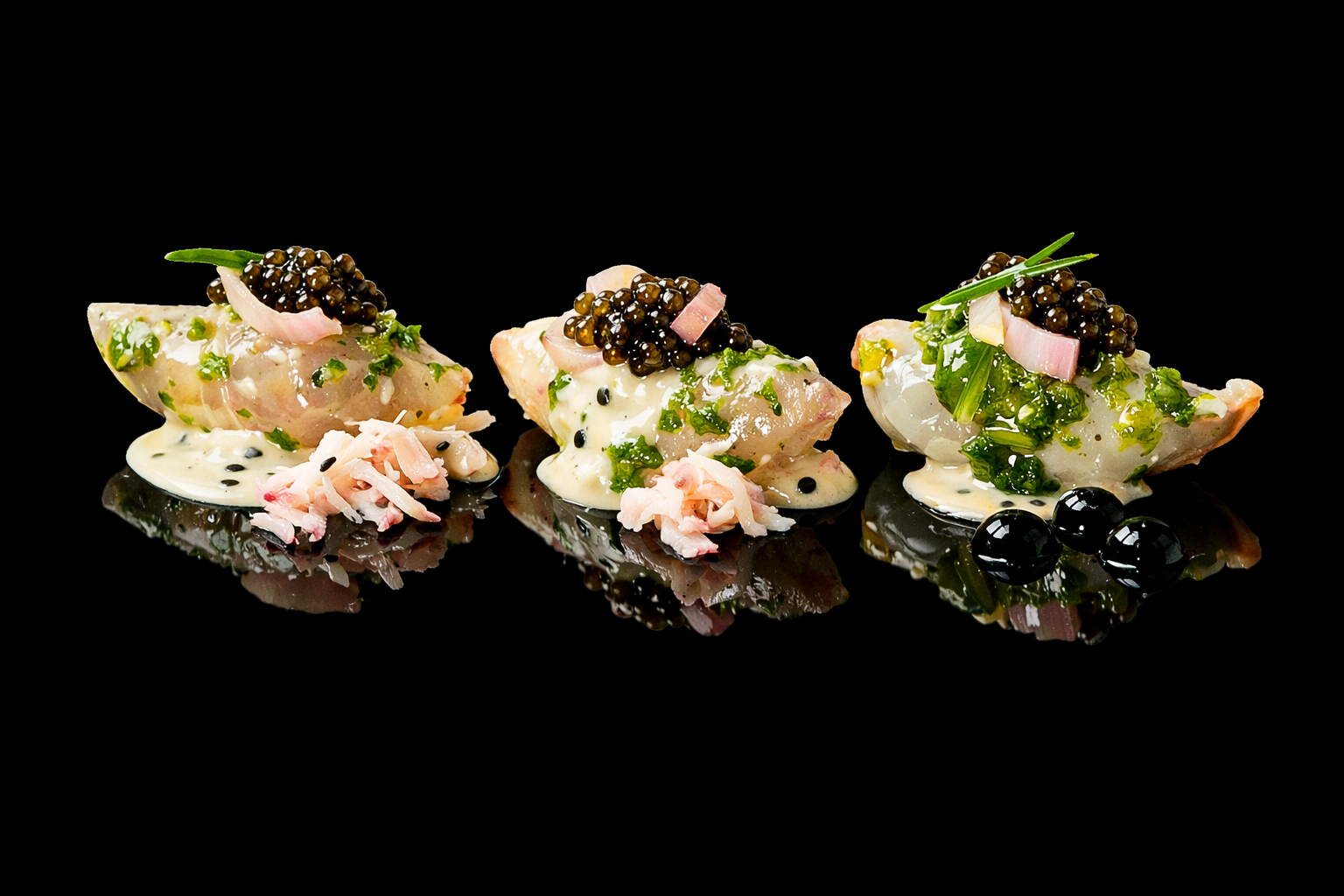 Trois pièces de sushi garnies de caviar, oignons rouges, herbes et sauce raffinée, sur une surface noire, avec des reflets.
